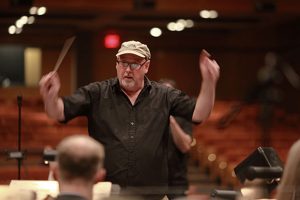 Charles Cozens arms raised conducts the Burlington New Millennium Orchestra